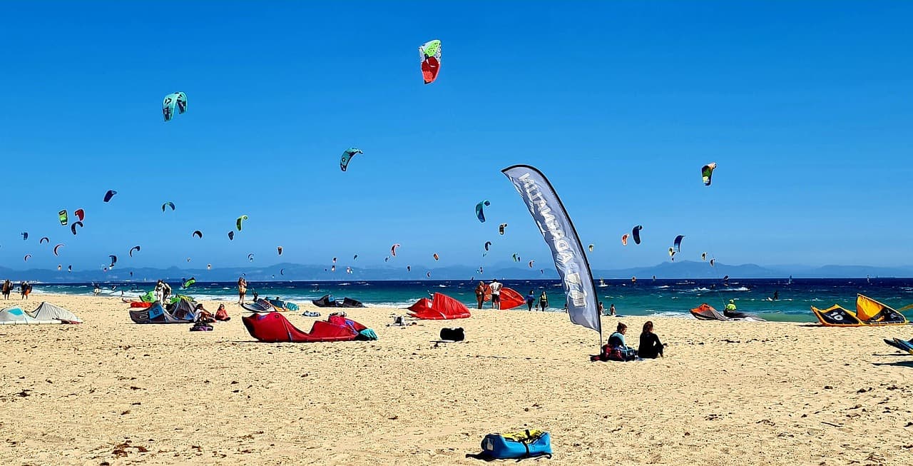 Playa de Los Lances en Tarifa con decenas de cometas de kitesurf sobre el mar y el pueblo al fondo