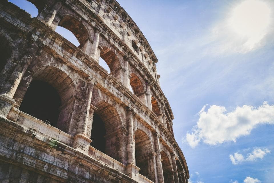 Fachada exterior del Coliseo de Roma con sus arcos de piedra recortados contra un cielo azul